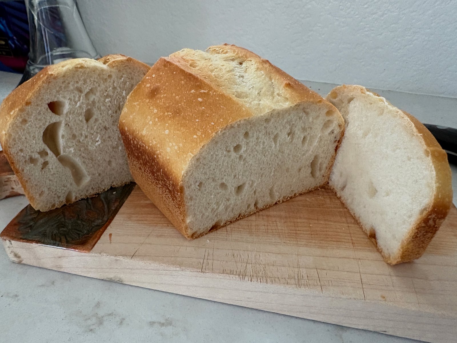 Sliced sandwich loaf showing open crumb on a wooden cutting board